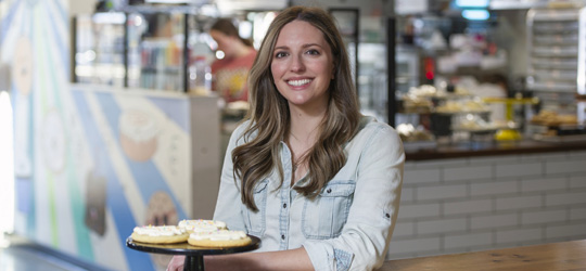 Business Member, Laura Y. standing in her bakery