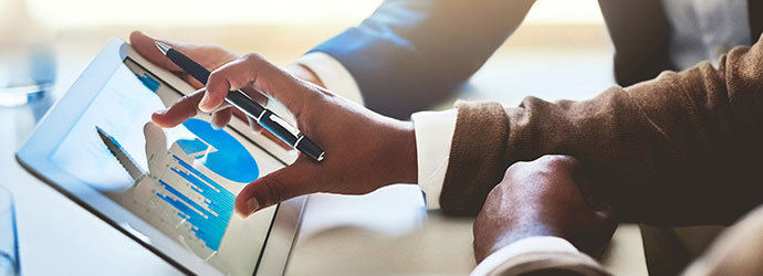 two hands touching a tablet with graphs on it